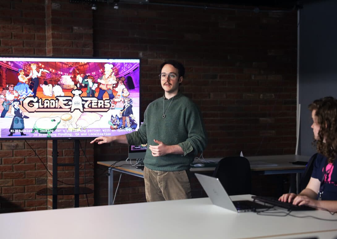 Young man standing in front of a screen, presenting for the game GladiEATers.