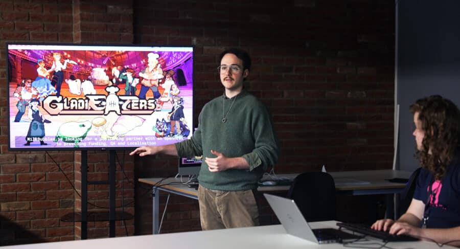 Young man standing in front of a screen, presenting for the game GladiEATers.