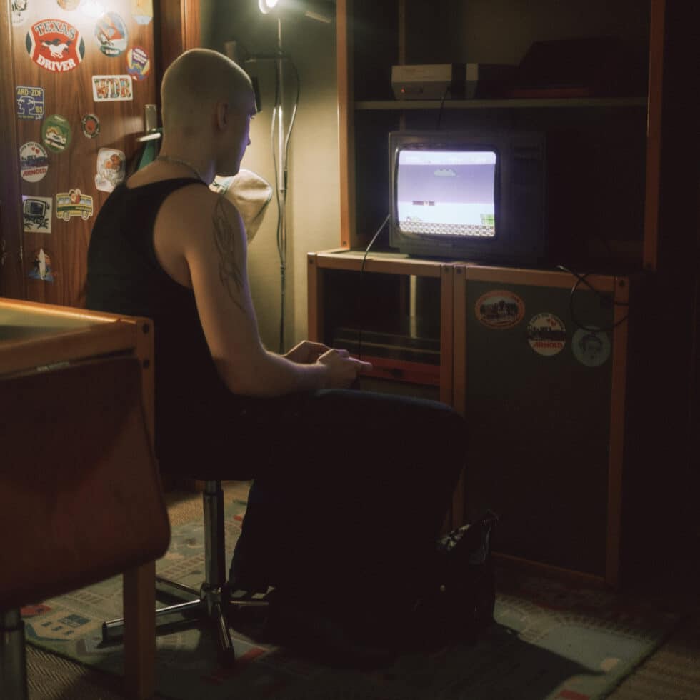 Solitary student playing on games console while seated in dim room