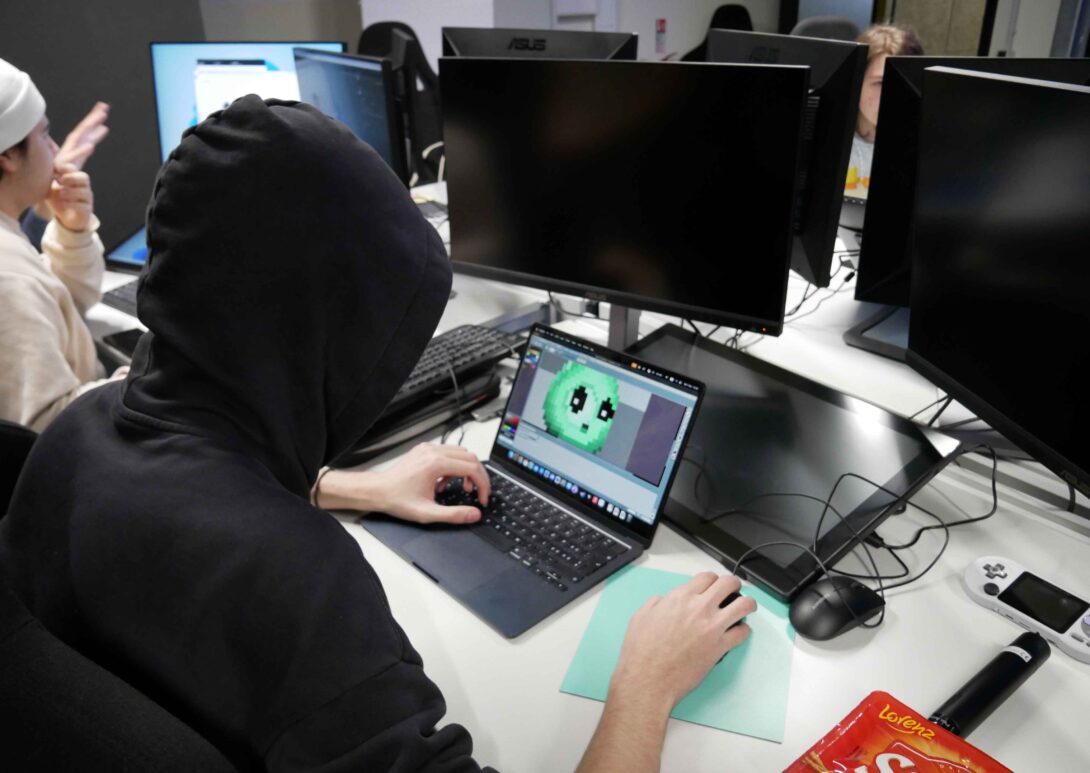 Student using computer and designing computer game character in class